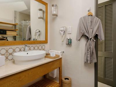 Modernes Badezimmer mit Waschbecken, Spiegel, Bademantel und Haartrockner.