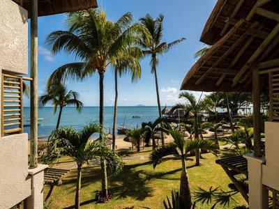 Blick auf einen tropischen Garten mit Palmen und Meer vom Balkon eines Hotels.