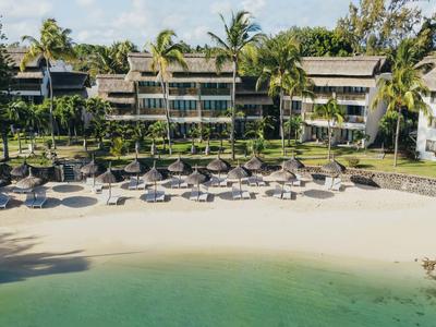 Hotel am Strand mit Sonnenschirmen, Palmen und türkisfarbenem Wasser.