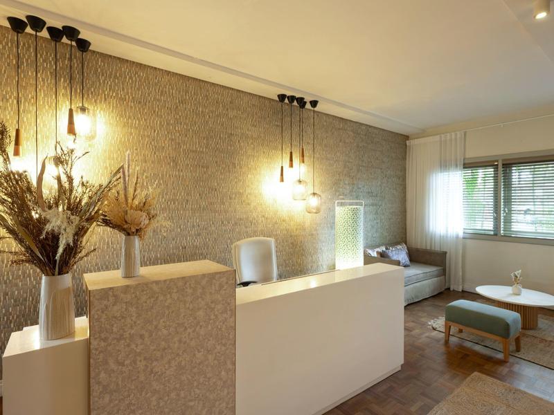 Moderne Empfangstheke mit hängenden Lampen, Trockenblumen und Sitzbereich mit Sofa und Hocker.