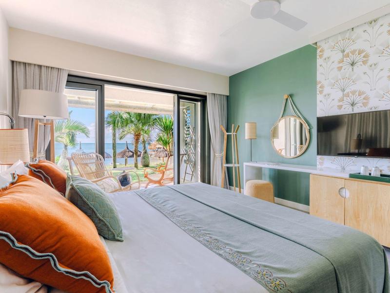 Helles Schlafzimmer mit grünem Akzent, Holzmo?beln, großem Bett und Blick auf Terrasse mit Palmen.