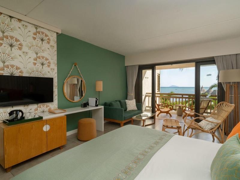 Gemütliches Hotelzimmer mit Balkon und Meerblick, eingerichtet mit Bett, Sofa und TV.