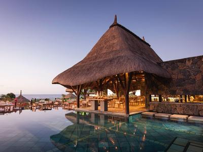 Pool mit offenem Pavillon und Blick auf das Meer bei Sonnenuntergang im Hotelresort.