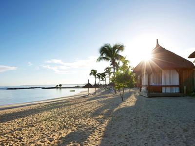 Plage avec palmiers et bungalows au coucher du soleil dans une station tropicale