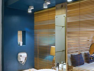 Salle de bain moderne avec vasque ronde blanche, miroir et accents en bois.