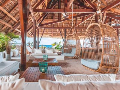Pavillon ouvert sur la plage avec des espaces de détente et vue sur la mer.
