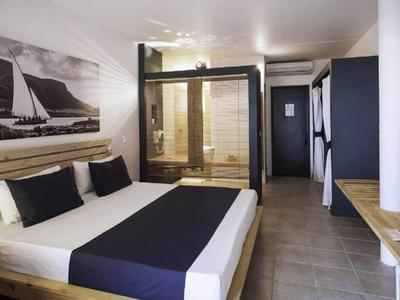 Modern eingerichtetes Hotelzimmer mit großem Bett, Bild an der Wand und begehbarer Dusche.