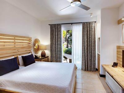 Chambre d'hôtel confortable avec lit double, ventilateur au plafond et accès à un jardin.