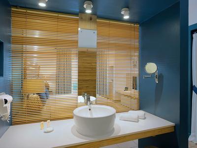 Salle de bain moderne avec lavabo rond, stores en bois et murs bleus.