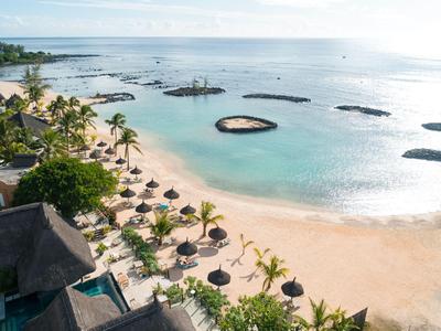 Strand mit Sonnenschirmen, Palmen und klarem Wasser an einem tropischen Reiseziel.