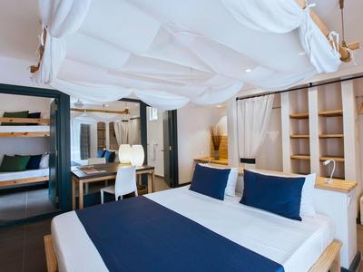 Modern eingerichtetes Hotelzimmer mit großem Bett, blau-weißer Bettwäsche und offenem Kleiderschrank.