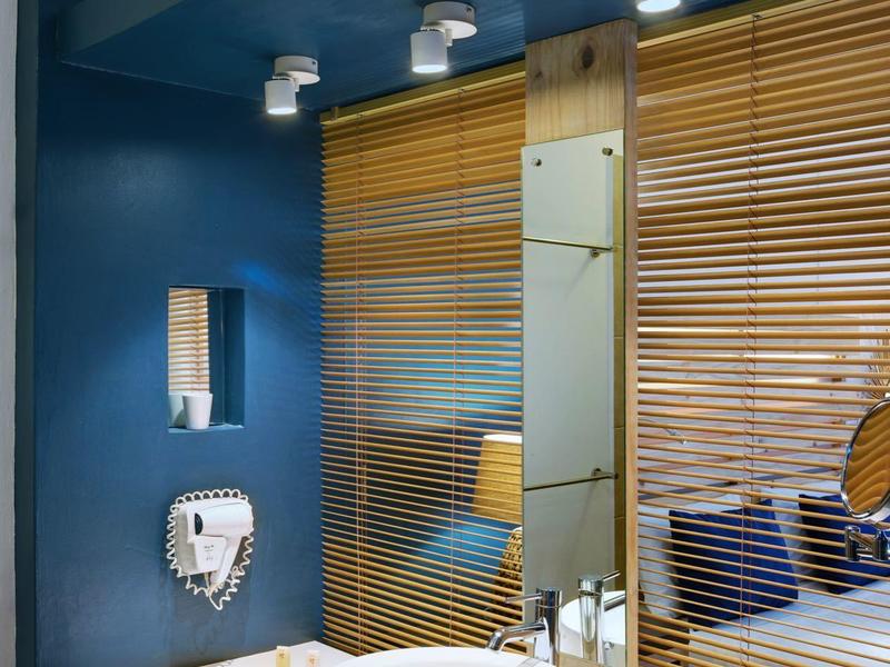 Salle de bain moderne avec vasque ronde blanche, miroir et accents en bois.