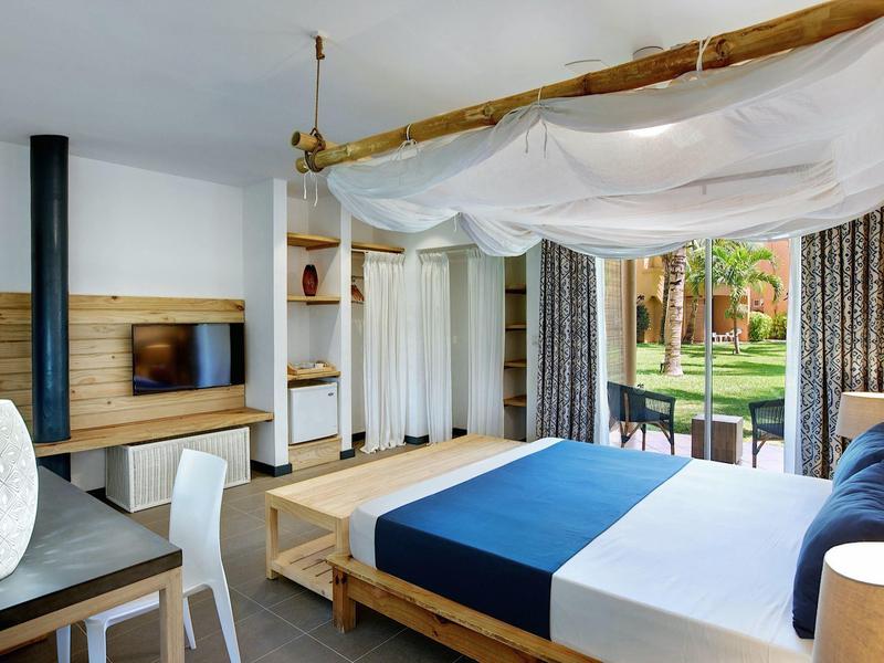 Chambre d'hôtel moderne avec lit à baldaquin et vue sur le jardin