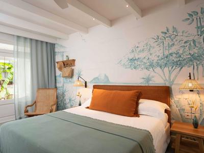 Modernes Schlafzimmer mit großem Bett, Wandkunst und natürlichem Licht durch ein Fenster.