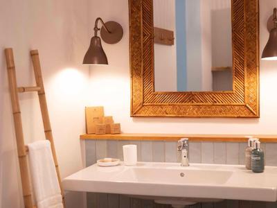 Helles Badezimmer mit rechteckigem Spiegel, Waschbecken und hölzerner Handtuchleiter.