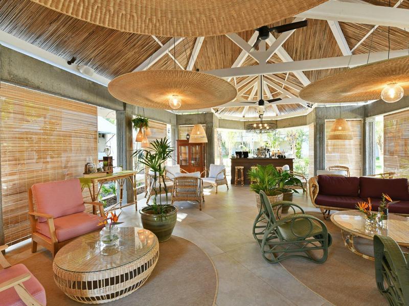 Hell eingerichteter Hotel-Loungesaal mit vielfältigen Sitzmöglichkeiten und Pflanzen.