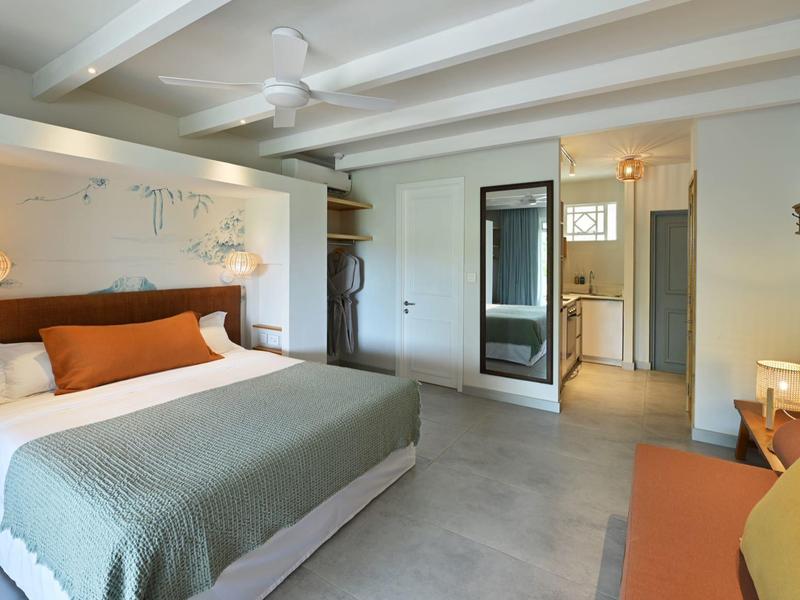 Modernes Hotelzimmer mit großem Bett, Deckenventilator und gemütlicher Einrichtung.