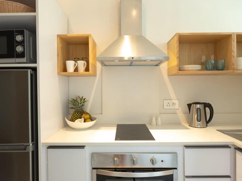 Moderne Küchenzeile mit Edelstahlofen, Induktionskochfeld, Kühlschrank und minimalistischem Design.