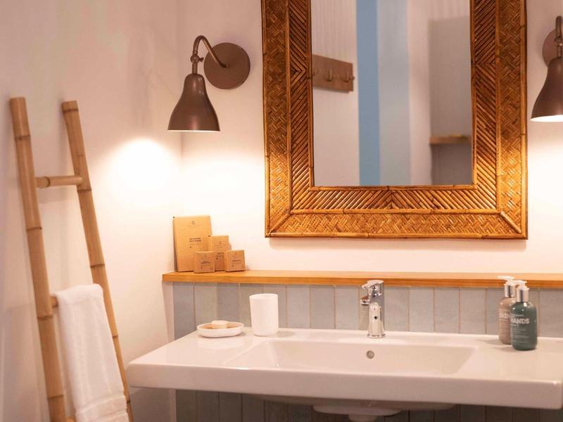 Helles Badezimmer mit rechteckigem Spiegel, Waschbecken und hölzerner Handtuchleiter.