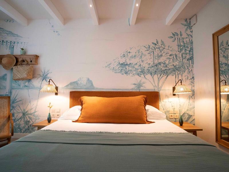 Gemütliches Hotelzimmer mit großem Bett, dekorativem Wandbild und warmem Licht.