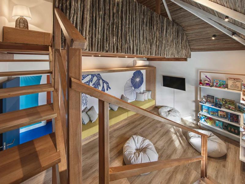 Gemütlicher Dachboden mit Holztreppe, Sitzsäcken, Bücherregal und hellen Holzbalken.