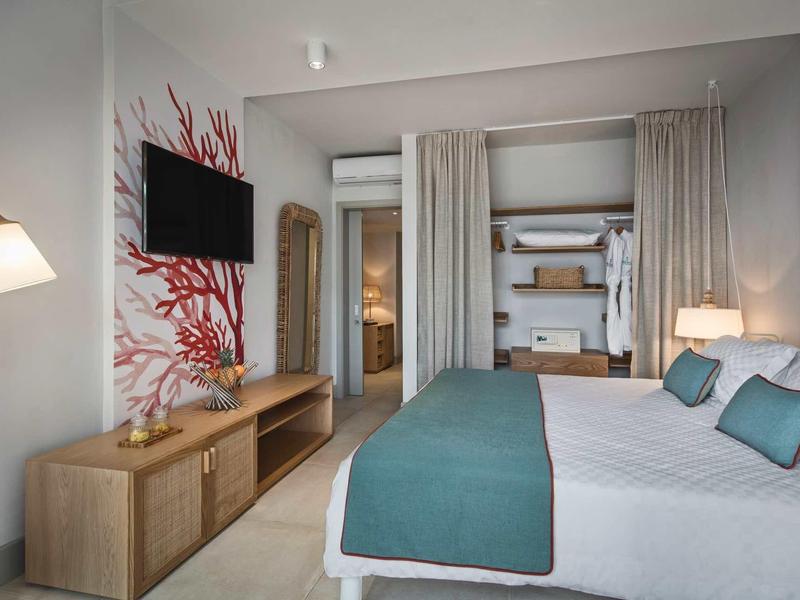 Elegantes Schlafzimmer mit Doppelbett, TV, Kommode, rotem Wandmotiv und beige Vorhängen.