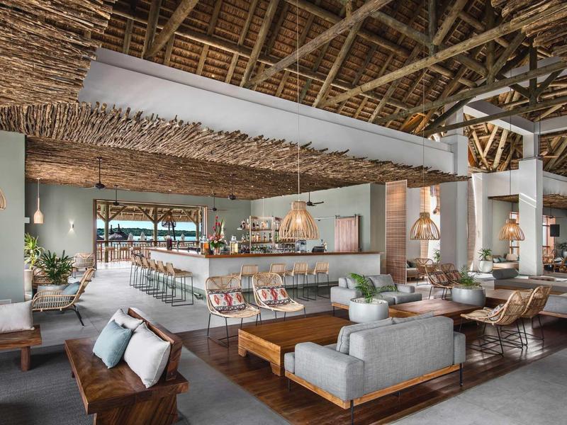 Großes, offenes Wohnzimmer mit Holzdach, Sofas, Holztischen und moderner, natürlicher Einrichtung.