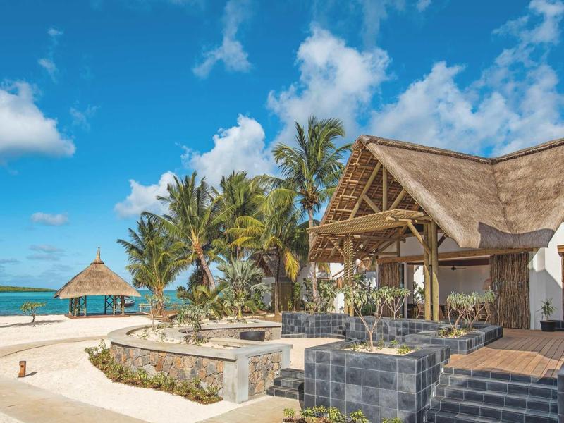 Tropisches Strandresort mit Palmen, Holzbungalow und klarem blauem Himmel.