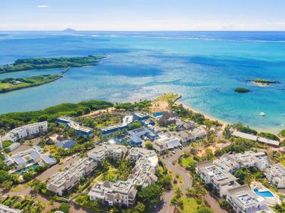 Vista aérea de un resort costero con edificios, playas y agua azul clara.