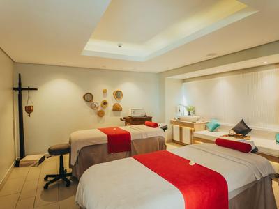 Habitación de spa luminosa con dos camas de tratamiento y decoración roja.