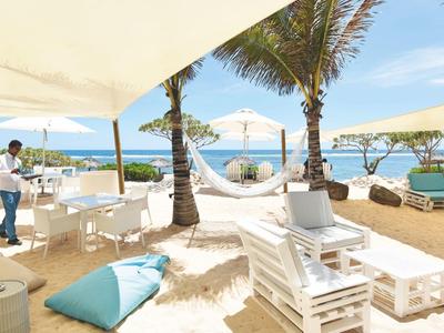 Beach terrace with white furniture, umbrellas, and sea view under clear sky.