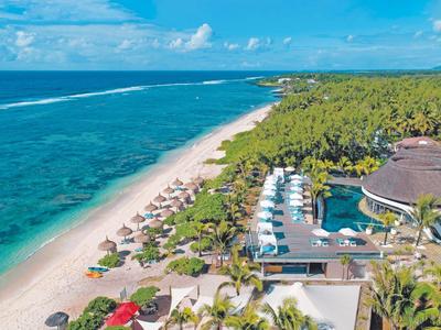 Aerial view of a tropical beach resort with pool and palm trees.