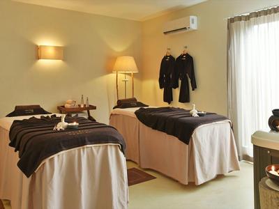 Treatment room with two massage tables, warm lighting, and a tea set by the window.