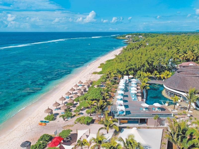 Aerial view of a tropical beach resort with pool and palm trees.