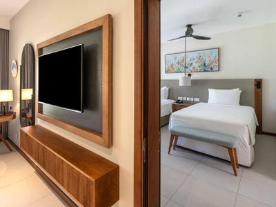 Modern eingerichtetes Hotelzimmer mit Fernseher, Schreibtisch, Doppelbett und dezentem Kunstbild.