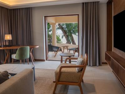 Moderner Wohnraum mit Holzstuhl, Arbeitsbereich, Schiebetür zum Balkon mit Tisch und Meerblick.