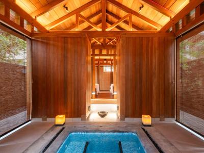 Luxuriöser Wellnessbereich mit Holzwänden, bequemen Sitzbänken und beleuchtetem Whirlpool.