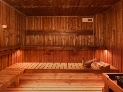 Holzsauna mit mehrstufigen Bänken, warmem Licht und Kopfstützen aus Holz und Stoff.