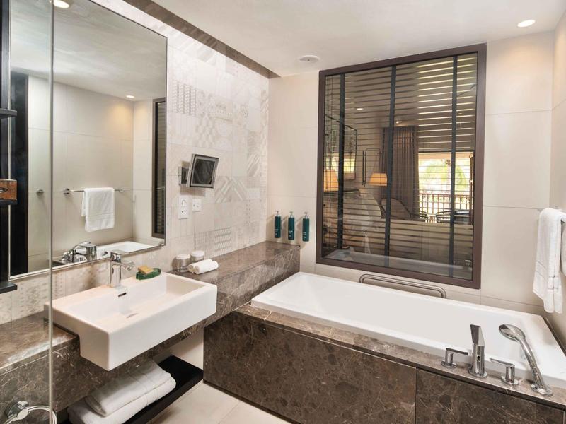 Modernes Badezimmer mit weißer Badewanne, großem Spiegel, Waschbecken und Marmorverkleidung.