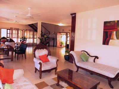 Salon lumineux avec meubles anciens, ventilateur de plafond et œuvre d'art moderne au mur.