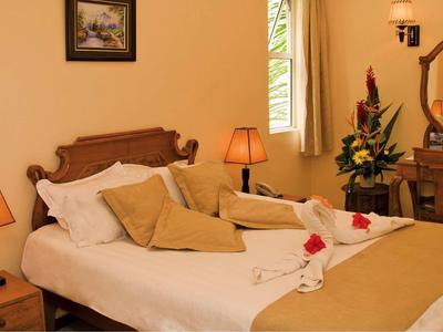 Gemütliches Hotelzimmer mit Doppelbett, dekorativen Kissen und Tischlampen.