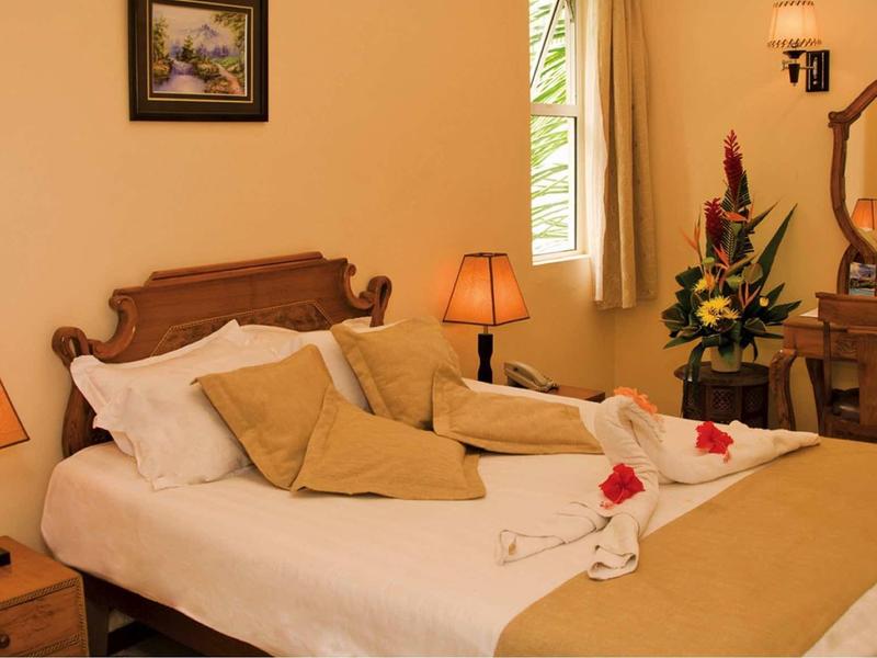 Chambre d'hôtel confortable avec lit double, lampes de chevet et une petite coiffeuse.