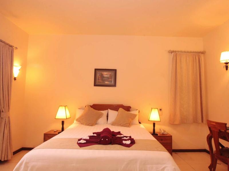 Chambre d'hôtel confortable avec lit double, lampes de chevet et éclairage chaleureux.