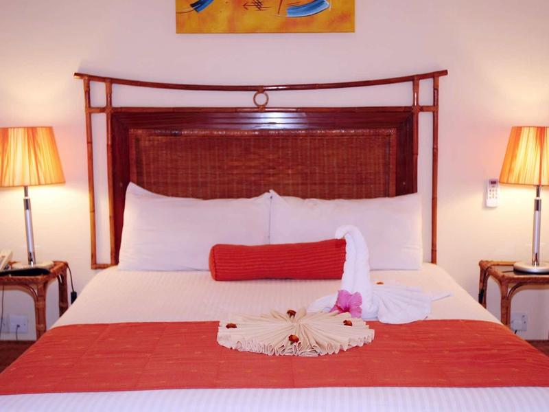 Chambre d'hôtel confortable avec grand lit, accents rouges et lumière chaude.