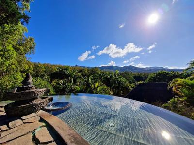 Piscina a sfioro con vista su colline boscose sotto un cielo azzurro terso in una giornata soleggiata