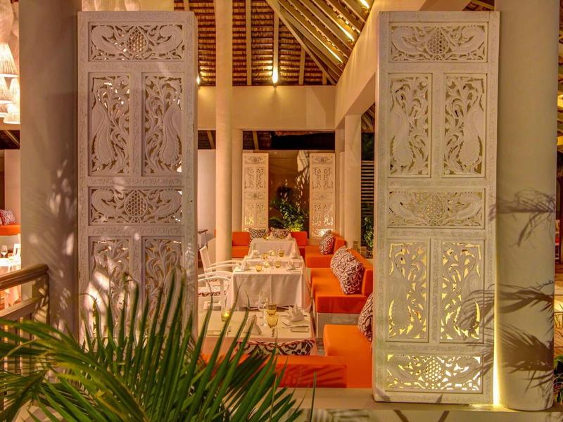 Otwarty wejście z misternie rzeźbionymi białymi drzwiami i przytulnymi miejscami do siedzenia w tle.