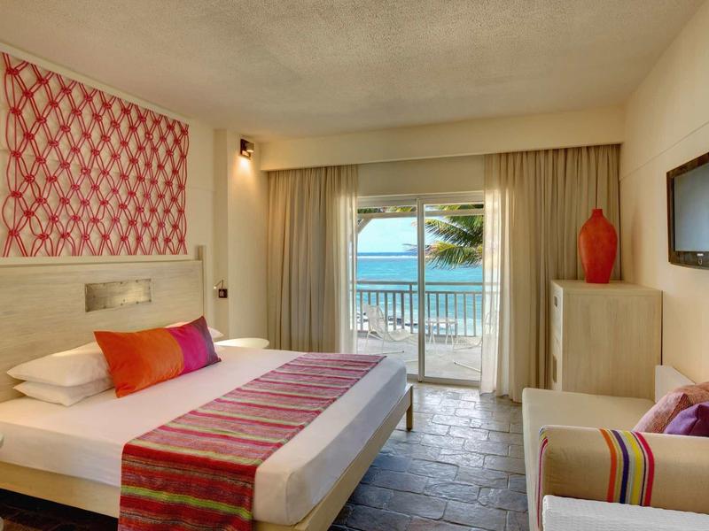 Jasny pokój hotelowy z podwójnym łóżkiem, balkonem z widokiem na morze i nowoczesnym wyposażeniem.