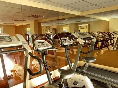 Palestra con diversi tapis roulant e parete a specchio in un hotel