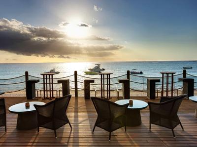 Terrazza con sedie e tavoli con vista sull'oceano al tramonto.