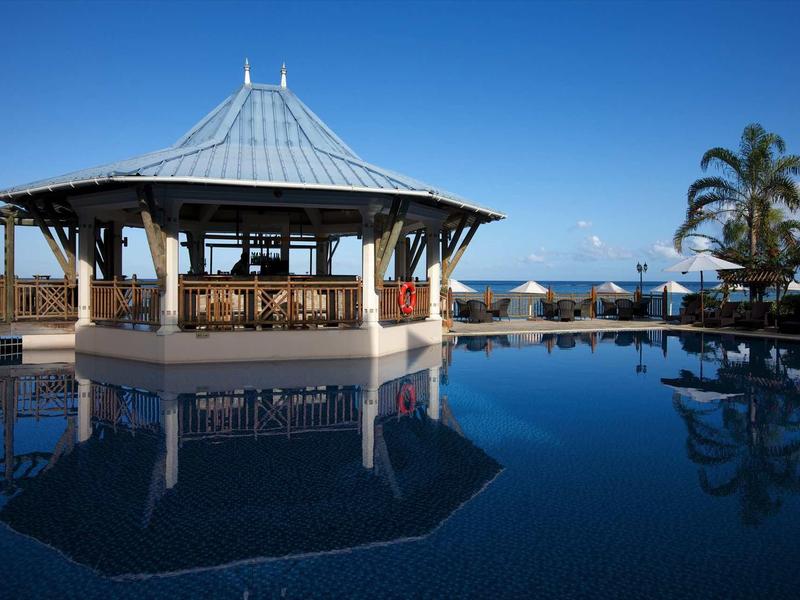 Padiglione aperto vicino a una piscina con vista sull'oceano sotto un cielo azzurro